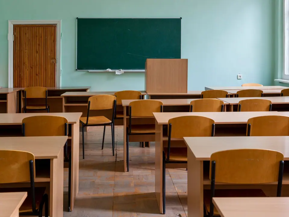 Ruang kelas kosong dengan meja kayu dan papan tulis hijau